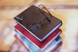 High angle view of stack of books with eyeglasses resting on top