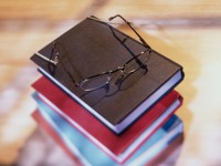 High angle view of stack of books with eyeglasses resting on top
